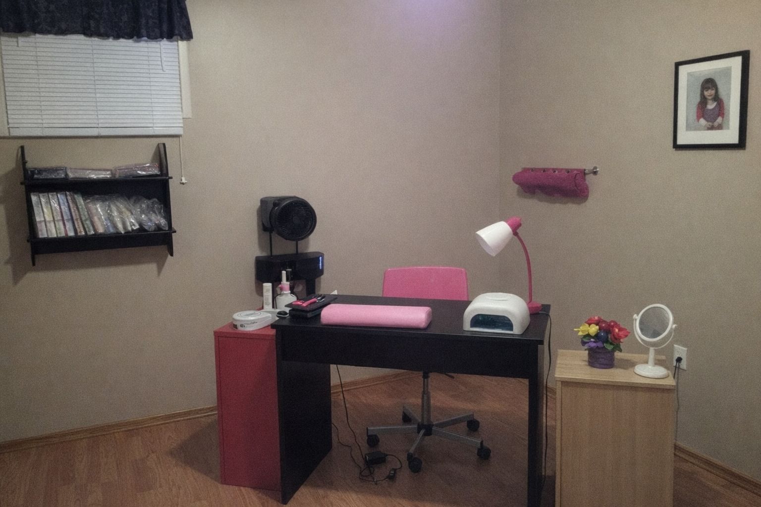 En arbetsstation för nagelteknolog med UV-lampa, arbetsbord och rosa detaljer.