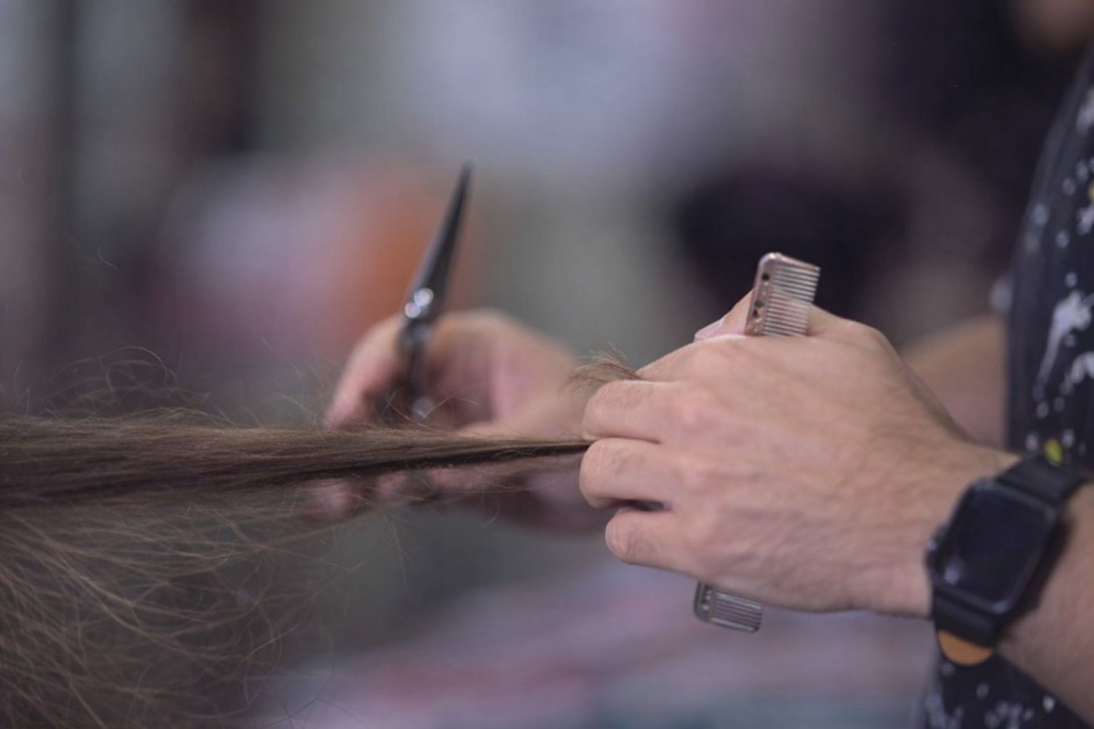 Händer som klipper hår under en praktisk skönhetsutbildning.